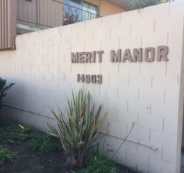 Merit manor front view with label on wall